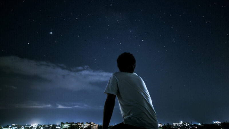 星と夜景を見る男性